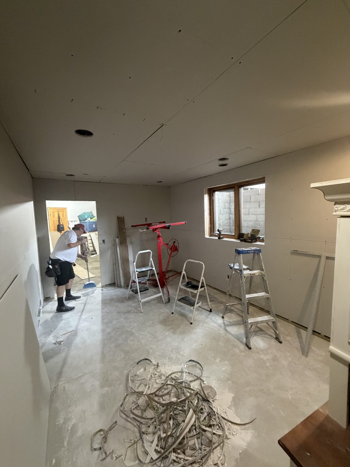 Same basement room with walls and ceiling fully hung in drywall, ready for tape